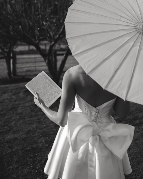 A black and white blog image of a bride with an umbrella facing away from the camera